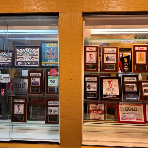 A display case filled with numerous awards and plaques for Little Nepal restaurant.