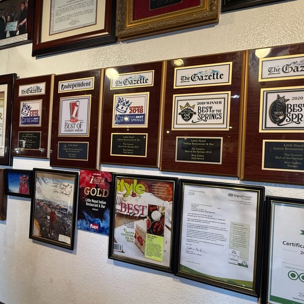 A wall covered with framed awards and certificates for Little Nepal Indian Restaurant & Bar.